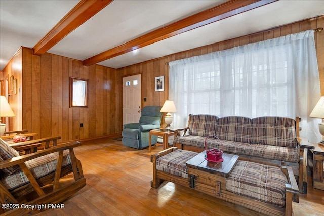 living room with wooden walls, beam ceiling, and light hardwood / wood-style flooring