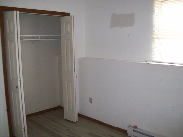 1166 Hunters Woods Dr, East Stroudsburg, PA 18301 - unfurnished bedroom with a baseboard heating unit, light wood finished floors, a closet, and baseboards