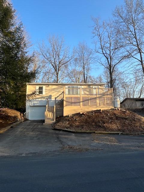 view of front of house featuring aphalt driveway, an attached garage, and a wooden deck