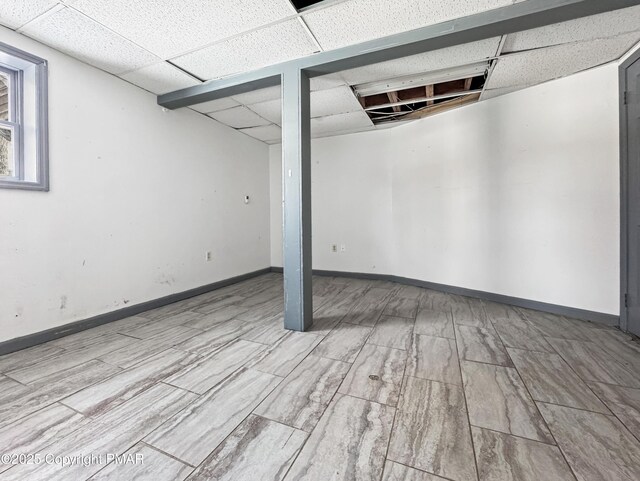 below grade area featuring a drop ceiling and baseboards