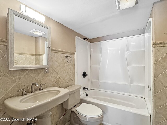 bathroom with shower / bathtub combination, a sink, toilet, and tile walls