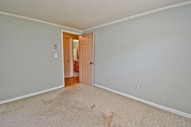 carpeted spare room with crown molding and baseboards