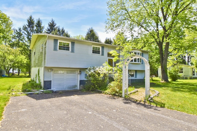 bi-level home with dirt driveway, a front lawn, and a garage
