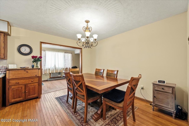 dining space featuring a notable chandelier, a textured ceiling, and light wood finished floors