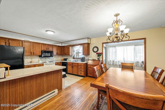 kitchen with a baseboard heating unit, black appliances, light countertops, and brown cabinets