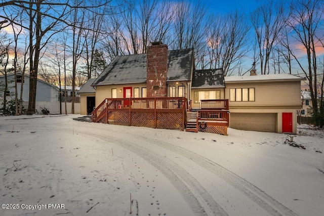 view of front of home with a deck, a chimney, and a garage