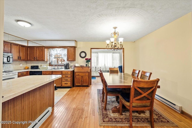 kitchen with light wood-style flooring, brown cabinets, an inviting chandelier, light countertops, and black appliances