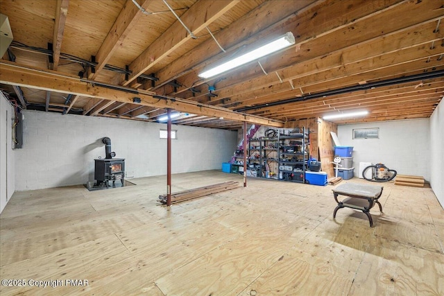 unfinished below grade area featuring a wood stove and electric panel