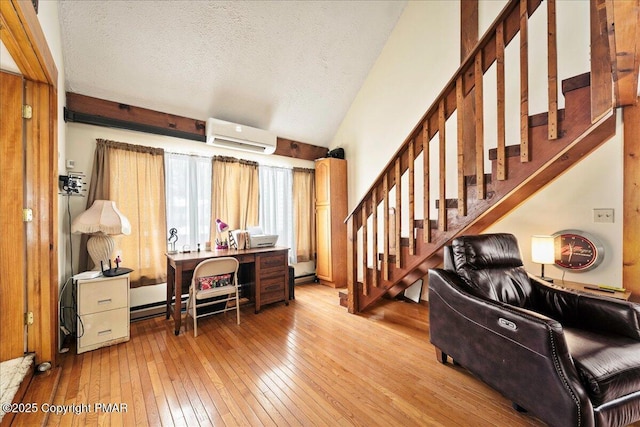 office space featuring lofted ceiling, hardwood / wood-style flooring, a textured ceiling, a baseboard heating unit, and a wall mounted AC