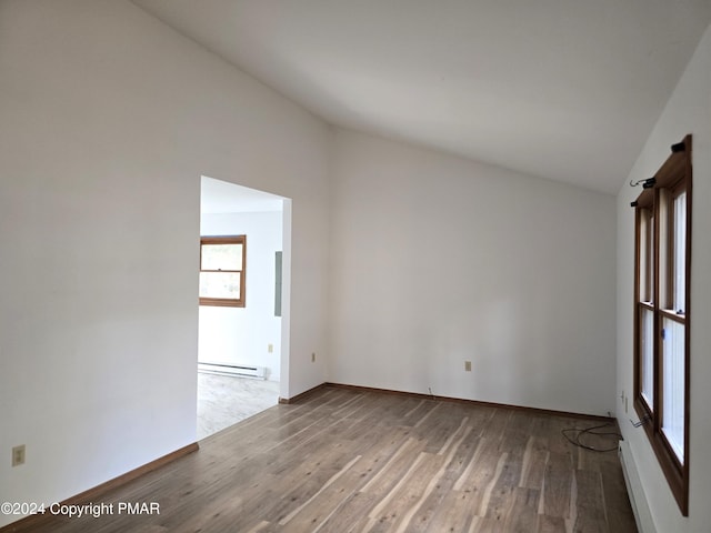 empty room with vaulted ceiling, a baseboard radiator, wood finished floors, and baseboards