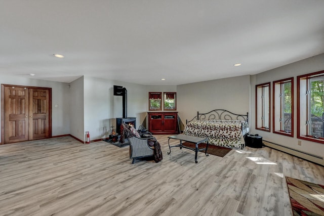 210 Egret Way E, Stroudsburg, PA 18302 - living room featuring wood finished floors, a baseboard radiator, recessed lighting, baseboards, and a wood stove