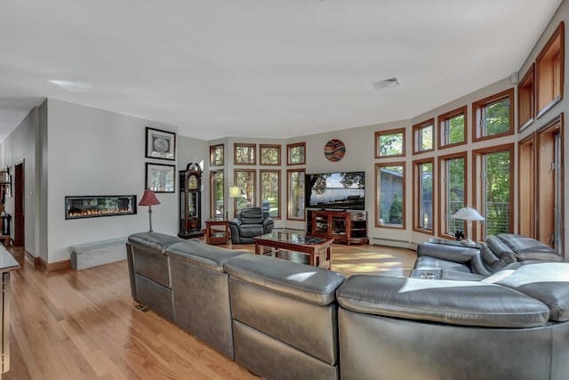 210 Egret Way E, Stroudsburg, PA 18302 - living area featuring baseboard heating, light wood finished floors, a glass covered fireplace, and baseboards
