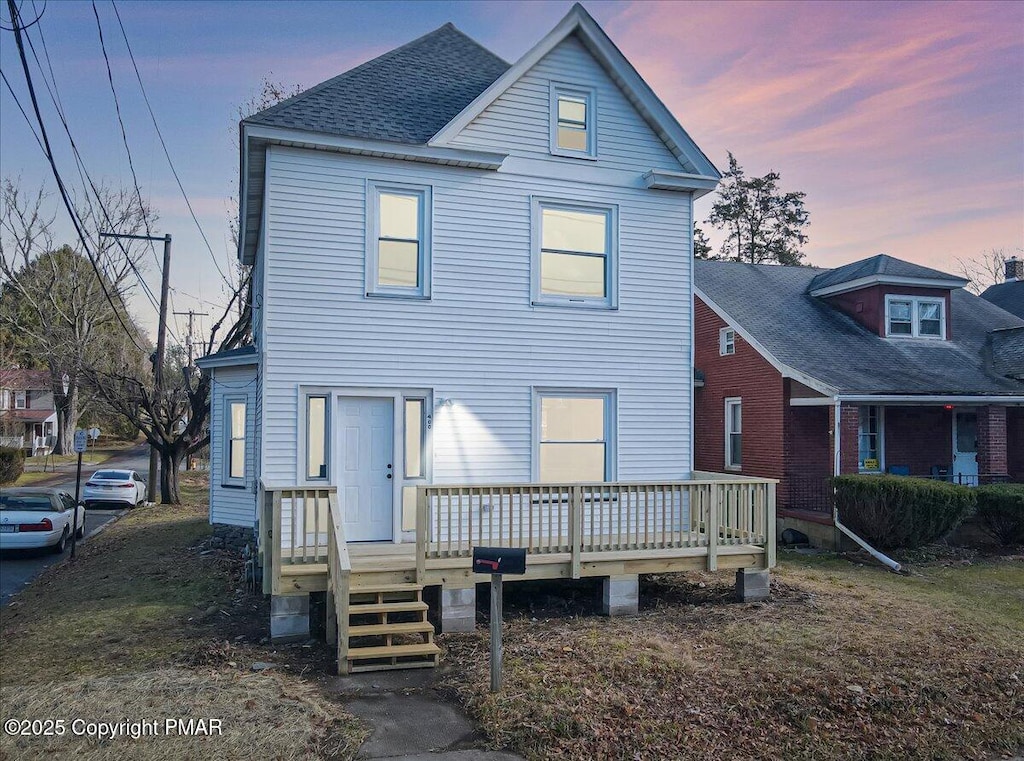 traditional-style home featuring a deck and roof with shingles