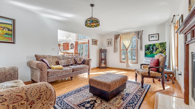 living room with light wood-style floors, plenty of natural light, a fireplace, and a chandelier