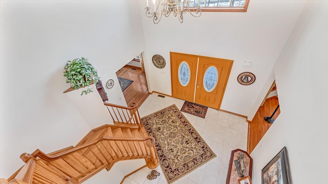 foyer with tile patterned floors, a notable chandelier, a towering ceiling, and stairs