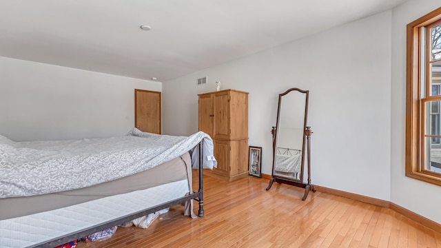 bedroom with light wood finished floors, baseboards, and visible vents