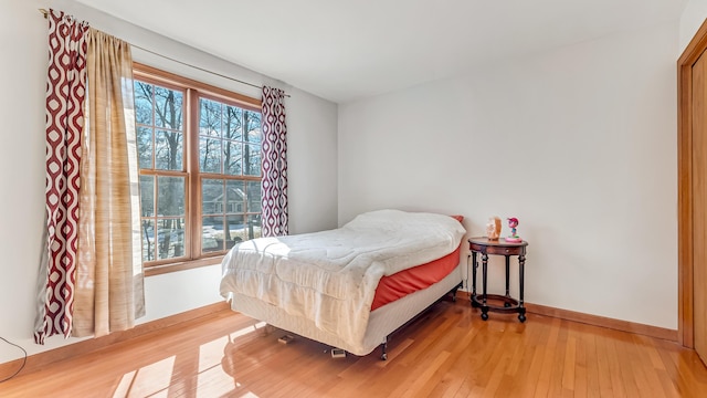 bedroom with light wood-type flooring, multiple windows, and baseboards