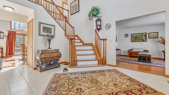 stairs with a towering ceiling, baseboards, and tile patterned floors