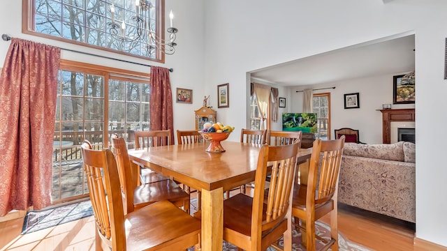 dining space with light wood-style floors, a fireplace, and a high ceiling