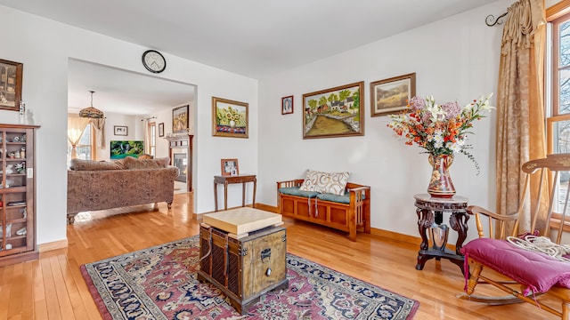 sitting room featuring a glass covered fireplace, hardwood / wood-style flooring, and baseboards