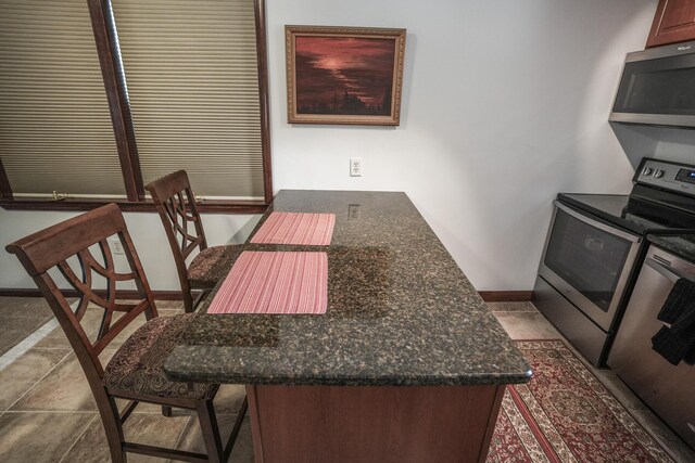 569 Lafayette Ave, Palmerton, PA 18071 - kitchen with appliances with stainless steel finishes, a kitchen bar, and dark stone counters