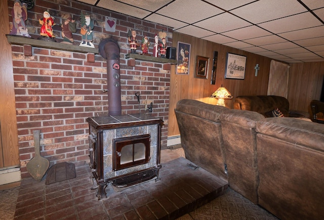 3193 Pine Ridge Dr, Bushkill, PA 18324 - living room with wooden walls, a wood stove, baseboard heating, and a drop ceiling