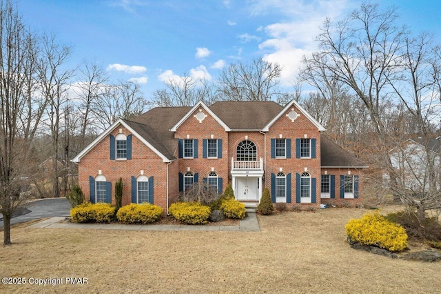 colonial inspired home with a front lawn and brick siding