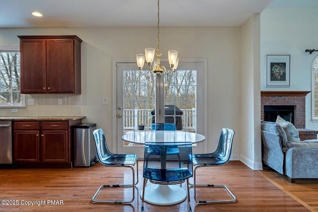 dining area with baseboards, wood finished floors, a fireplace, a notable chandelier, and recessed lighting