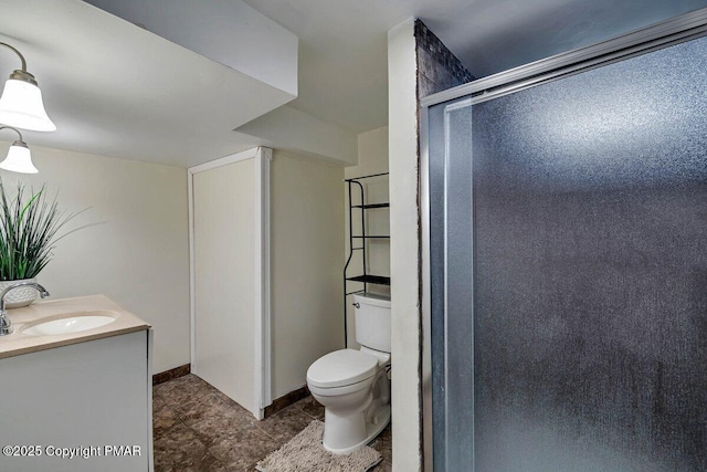 bathroom featuring tile patterned flooring, toilet, vanity, baseboards, and a stall shower