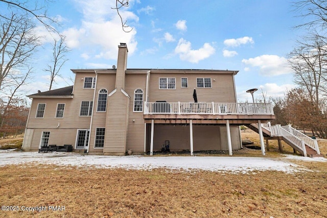 rear view of house featuring stairway, a chimney, and a wooden deck