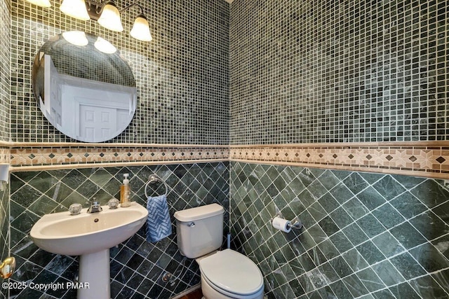 bathroom with toilet and tile walls