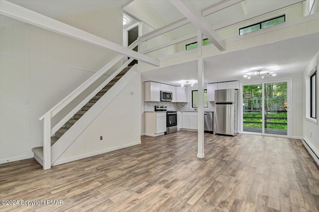 unfurnished living room with a high ceiling, stairway, and light wood-type flooring