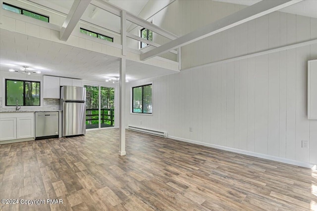 unfurnished living room featuring a wealth of natural light, a baseboard radiator, and light wood finished floors