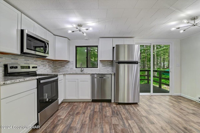 kitchen featuring stainless steel appliances, wood finished floors, a sink, and decorative backsplash