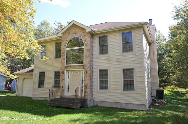 colonial inspired home with a garage, central AC unit, and a front yard