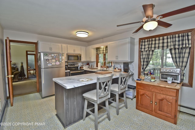 4462 Woodside Dr, East Stroudsburg, PA 18301 - kitchen featuring stainless steel appliances, light countertops, a peninsula, white cabinetry, and a breakfast bar
