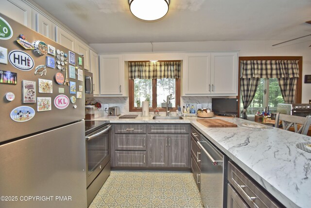 4462 Woodside Dr, East Stroudsburg, PA 18301 - kitchen featuring stainless steel appliances, decorative backsplash, white cabinetry, and light stone counters