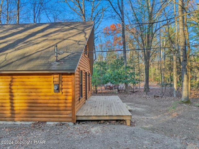 view of home's exterior featuring roof with shingles and a wooden deck