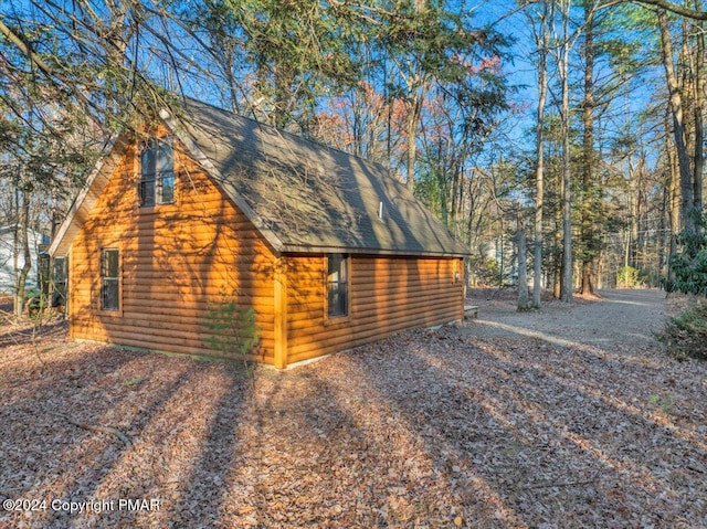 view of property exterior with a shingled roof and faux log siding