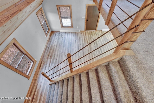 stairway with a baseboard radiator and wood finished floors