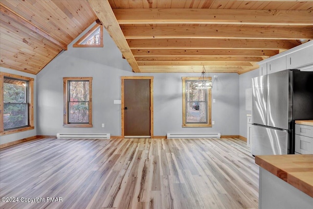 interior space with lofted ceiling with beams, light wood finished floors, a baseboard radiator, and baseboards