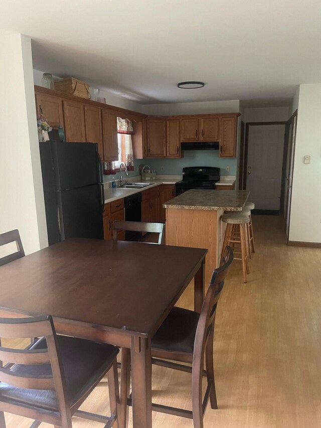 2852 Oak View Ln, Tobyhanna, PA 18466 - kitchen with black appliances, a center island, under cabinet range hood, light wood-type flooring, and brown cabinetry