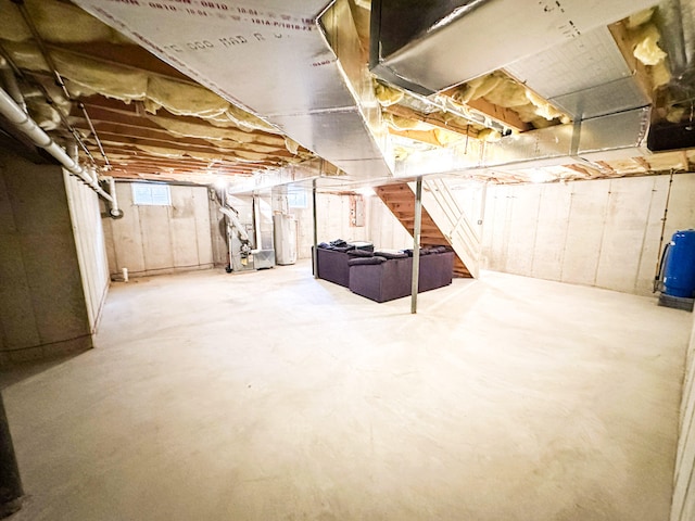 basement featuring water heater, stairs, and a water pressure tank