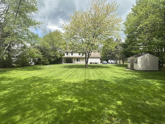 view of green lawn with a shed, an outdoor structure, and view of wooded area