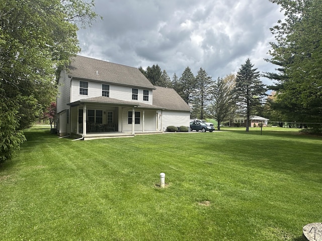 rear view of property featuring a yard and a patio area
