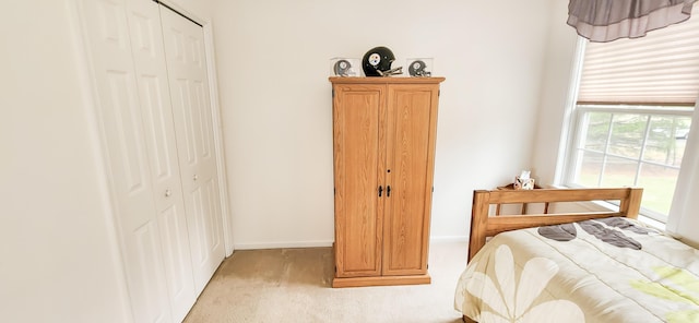 bedroom with light colored carpet, a closet, baseboards, and access to outside