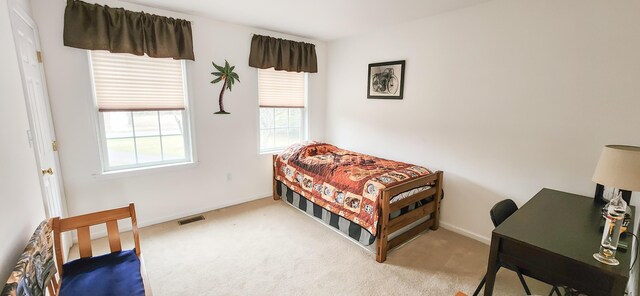 carpeted bedroom featuring baseboards and a desk