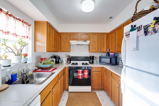 kitchen with under cabinet range hood, white appliances, a sink, visible vents, and light floors