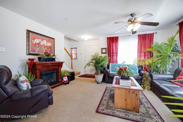 living room with carpet, stairway, ceiling fan, and a glass covered fireplace