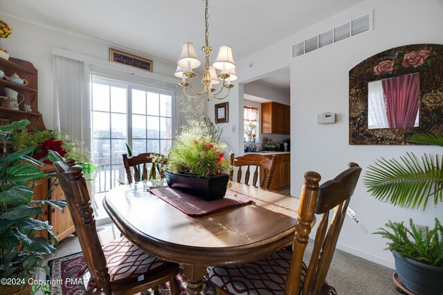 dining space with light colored carpet, visible vents, a notable chandelier, and baseboards